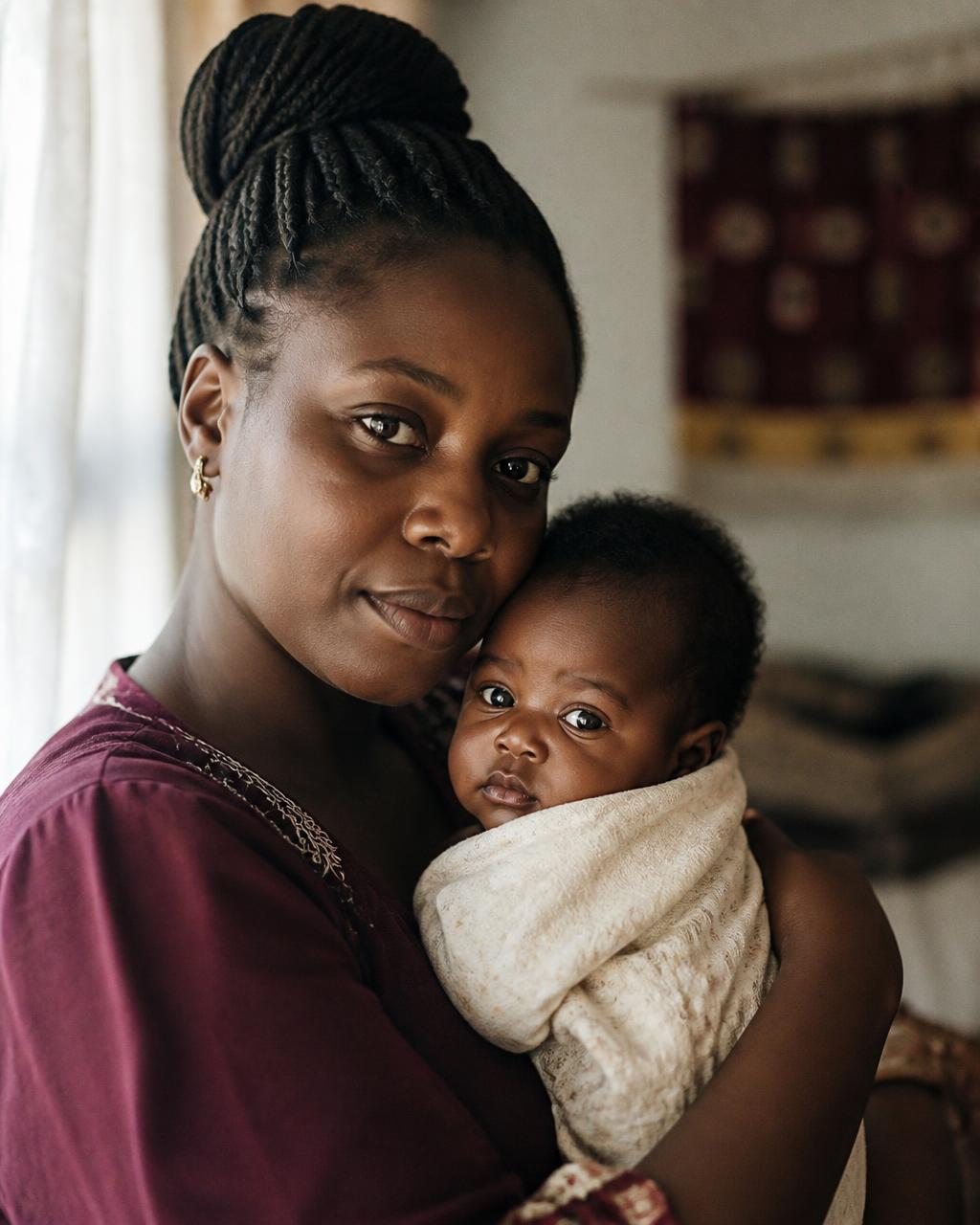 An African mother holding her infant, bathed in warm window light